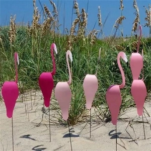 Pink flamingo swirl bird garden stakes in a lush outdoor backyard lawn setting