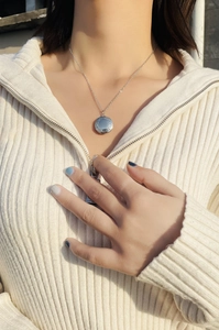Silver round floating locket necklace with vintage relief texture on model