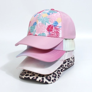 Stack of baseball caps featuring tropical pineapple, floral, and leopard print designs