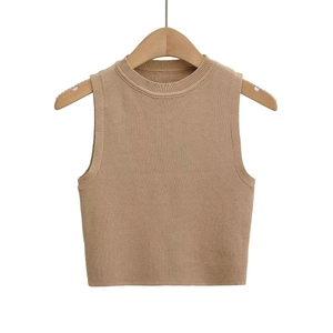 Detail of camel knitted sleeveless tank top fabric on a wooden hanger with white backdrop