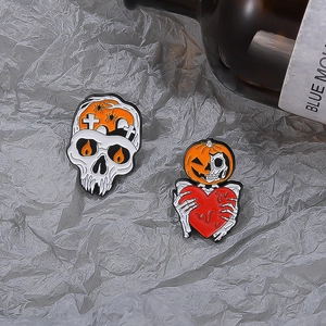 Detail of Halloween enamel pins set featuring skeleton and pumpkin designs on folded paper