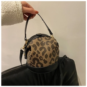 Detail of leopard print cylinder handbag with black leather trim and gold hardware