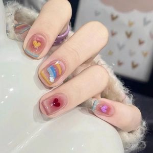 Close-up of short square press-on nails with colorful French tips and heart patterns