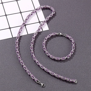 Detail of purple Byzantine link chain necklace and bracelet set on dark textured surface
