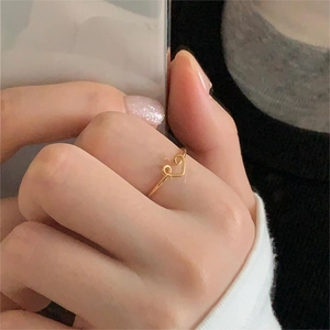 Detailed view of a minimalist heart-shaped gold ring worn on a finger with a clean design