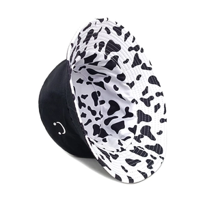 Reversible bucket hat with black smile embroidery and cow print pattern