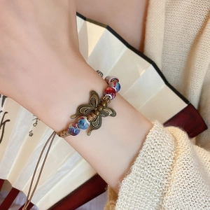 Macro detail of butterfly charm and colorful ceramic beads on woven rope bracelet