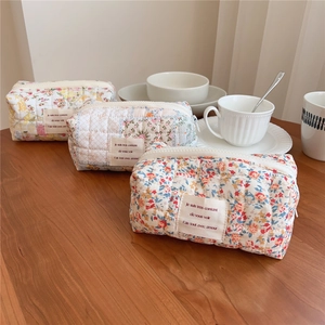 Detailed view of quilted cotton floral cosmetic bags on a wooden table setup