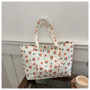 Close-up of off-white canvas tote bag with vibrant cherry prints on a wooden desk