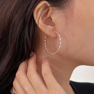 Minimalist silver twist hoop earrings in 925 sterling silver for women on a model