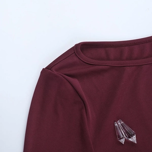 Close-up of burgundy ribbed knit fabric with decorative crystal prism pendants on clothing