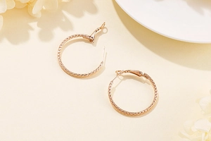 Macro shot of rose gold hoop earrings with textured geometric knurling pattern