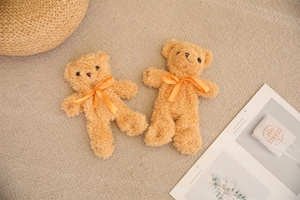 Detail of small teddy bear plush dolls with orange bows on a cozy textured carpet