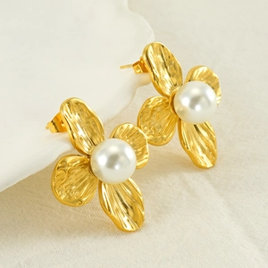 Detail of golden flower stud earrings with hammered metal petals and round white pearls