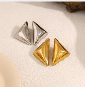 Vista macro di orecchini geometrici a triangolo con finitura lucida in oro e argento