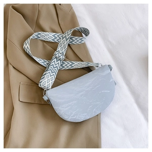 Detail of grey saddle bag with marble texture and geometric woven shoulder strap on a blazer