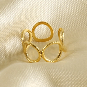 Detail of 18k gold irregular oval ring on luxury champagne silk fabric background