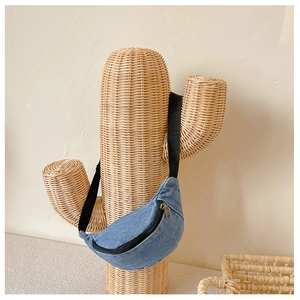 Detail of blue denim kids fanny pack hanging on a creative cactus prop against a warm wall