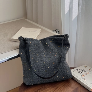 Detail of grey wool tweed tote bag with colorful dots and black leather shoulder strap