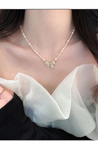 Close-up van elegante Franse retro parelketting met sprankelende strikhanger van zirkoon
