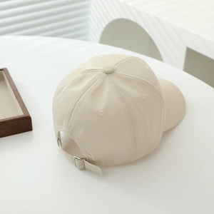 Detail view of beige cotton baseball cap with adjustable metal buckle and strap