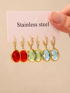 Macro shot of colorful faceted oval glass charms on stainless steel huggie earrings set