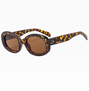 Detail of tortoise shell oval sunglasses featuring three metal studs and brown lenses