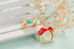 Close-up of colorful enamel adjustable gold rings with rhinestones on a mini wood tray