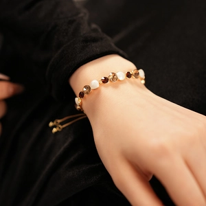 Détail d'un bracelet doré ajustable avec pierres d'opale blanche et cristaux marrons