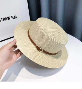 Detail of straw hat with brown leather band and golden metal buckle for sun protection