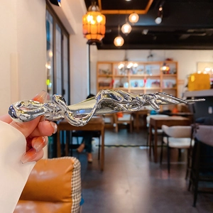 Close-up of a silver liquid metal butterfly hair clip with high-gloss mirror finish