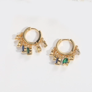 Détail macro de boucles d'oreilles dorées avec cinq breloques en zircon sur fond blanc