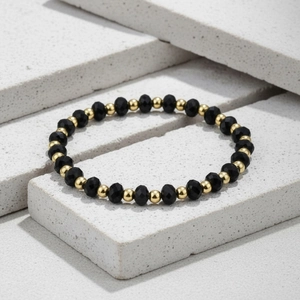 Macro detail of 4mm faceted black stone beads with gold plated spacer beads