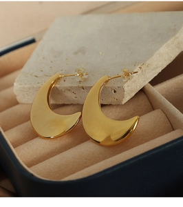 Macro shot of polished gold crescent moon earrings on stone in a jewelry box