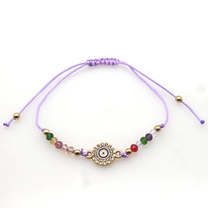 Detail of blue evil eye charm with crystal beads on a purple braided adjustable bracelet