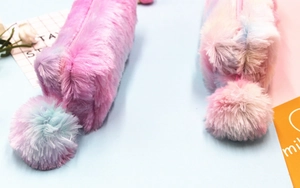 Detail of plush rainbow pencil case with soft faux fur texture and fuzzy pom-pom pendant