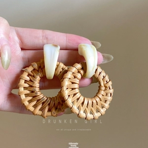 Detailed macro view of handmade raffia fan earrings with marble resin studs and woven texture