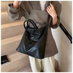 Detailopname van de grote zwarte leren shopper met glanzende afwerking en handvatten