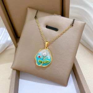 Detail of gold floral necklace with blue and white enamel, pearl and ruby in a box
