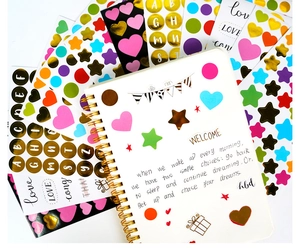 Detailed view of gold foiled heart and star stickers on a spiral notebook page