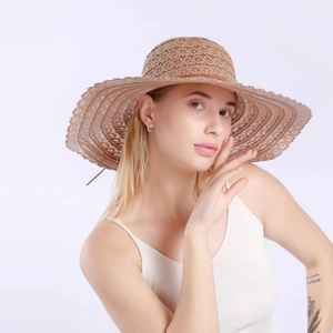 Close-up of woven straw hat with hollow wave pattern and brown leather strap detail