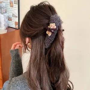 Brown plush bear hair claw clip with bow shown in a cozy hairstyle for women