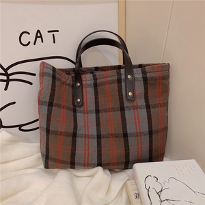 Detail of vintage plaid canvas tote bag with brown leather handles and gold rivets