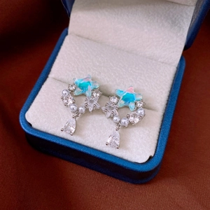 Macro shot of silver star-shaped earrings with blue stones and pearls in a jewelry box