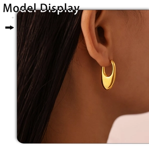 Close-up of model wearing thick gold U-shape earrings with polished mirror finish