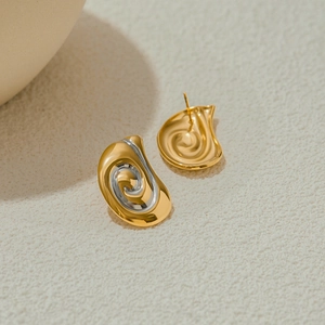 Dettaglio di orecchini a spirale bicolore oro e argento con texture moderna