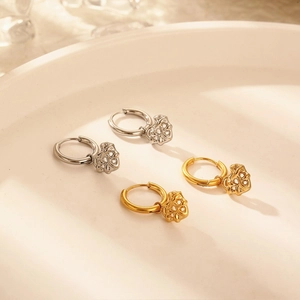 Modern gold and silver hoop earrings with hollow heart pendants on a ceramic plate
