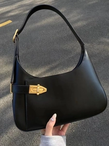 Detail of minimalist black leather hobo bag with a gold metal buckle and smooth texture