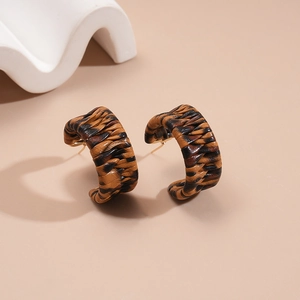 Macro detail of leopard print braided C-shape hoop earrings with gold metal needles