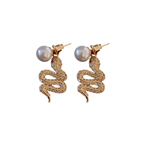Golden snake earrings with zircon crystals and dangling white pearl charms on white background